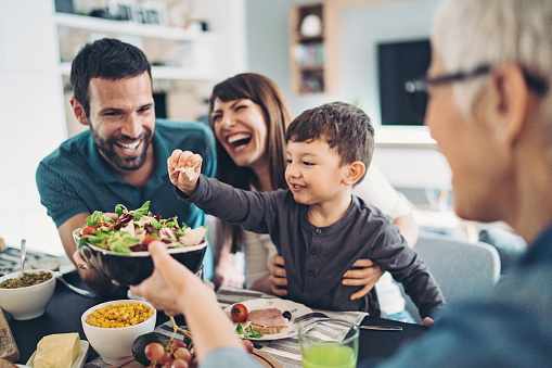 Photo of a family laughing as they are enjoying mealtime together.